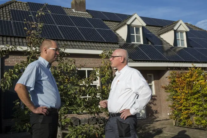 Leo van der Grinten in gesprek met een tevreden klant voor het huis waar de zonnepanelen succesvol op geïnstalleerd zijn