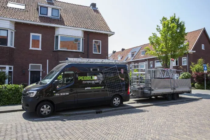 Bus van Pebble Zonnepanelen bij een project in Breda met aanhanger achter de bus