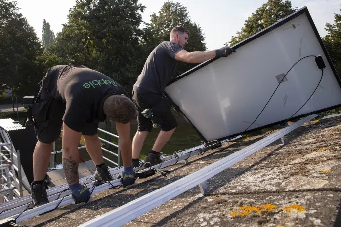 Installateurs van zonnepanelen op een dak die een zonnepaneel op een montageframe monteren