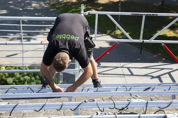 Een monteur van Pebble Zonnepanelen die bezig is met de installatie van het montageframe voor zonnepanelen op een dak