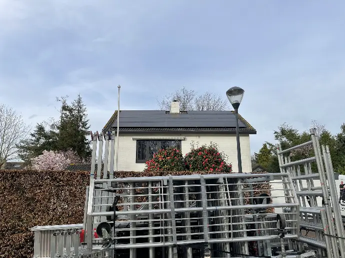 Een dak van een Bredase woning met zonnepanelen en steigers ervoor